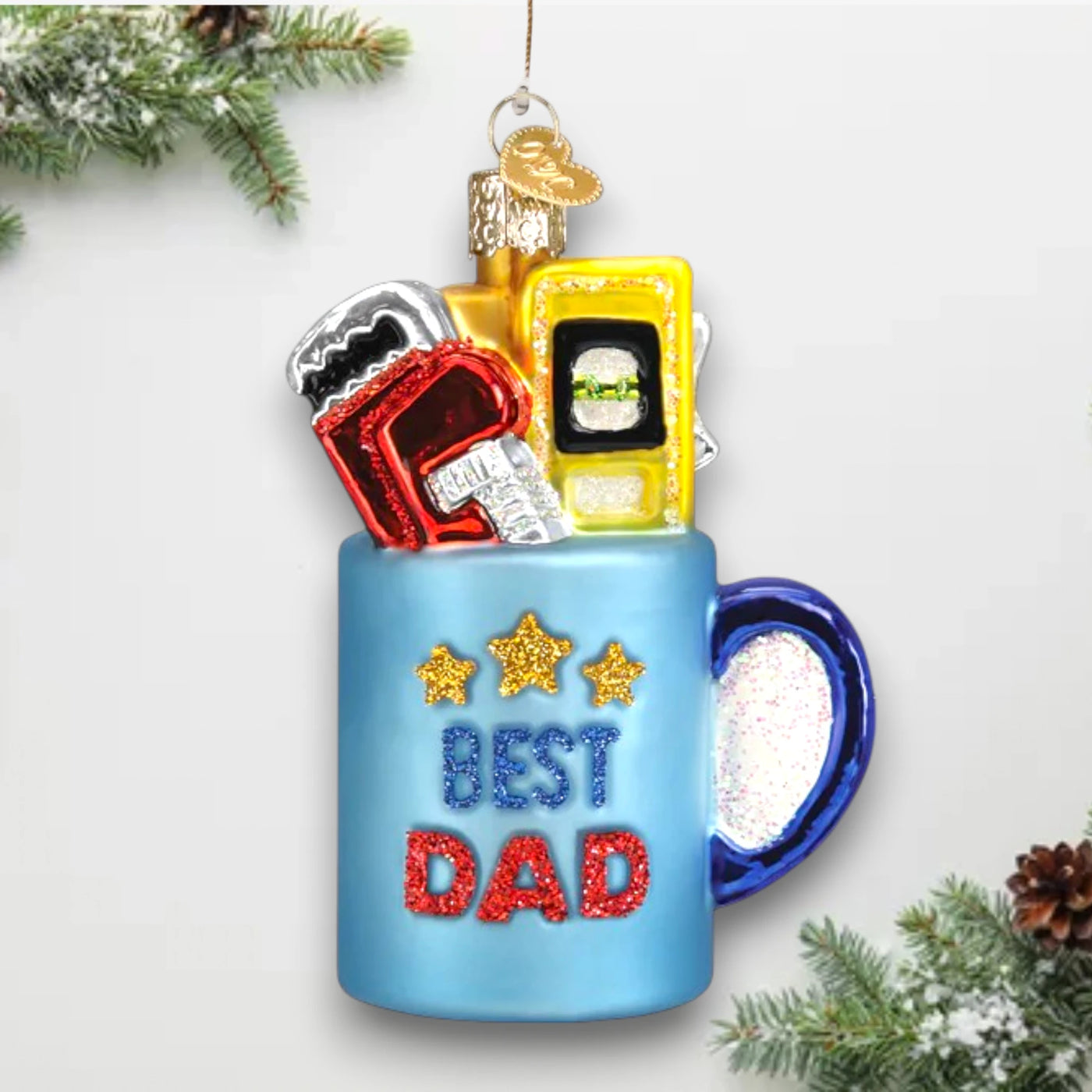 Blue “Best Dad” mug Christmas ornament featuring glittery stars, bold lettering, and colorful tools, customizable with name and year.