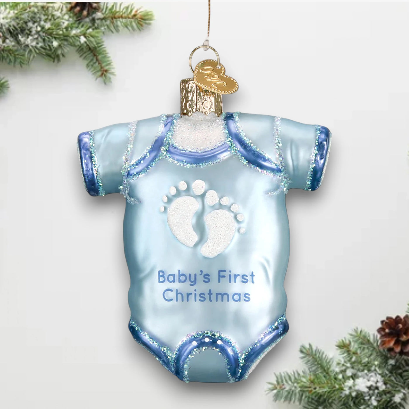 Blue baby onesie Christmas ornament featuring glittery footprints and the phrase “Baby’s First Christmas,” perfect for commemorating a baby’s first holiday.