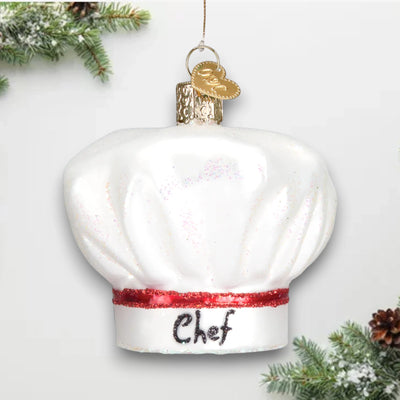 White chef’s hat Christmas ornament with a red glitter band and “Chef” written on the front, featuring elegant shimmering details.