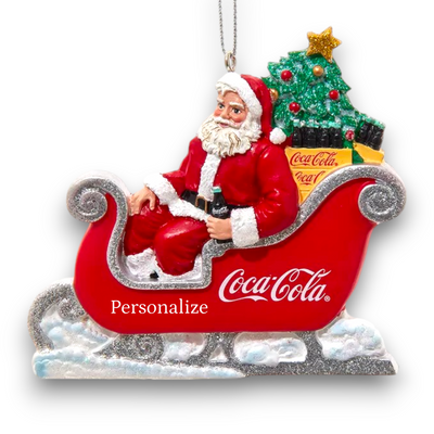 Close-up of Santa Claus holding a Coca-Cola bottle while sitting in a red sleigh, highlighting the ornament's craftsmanship and vintage charm.