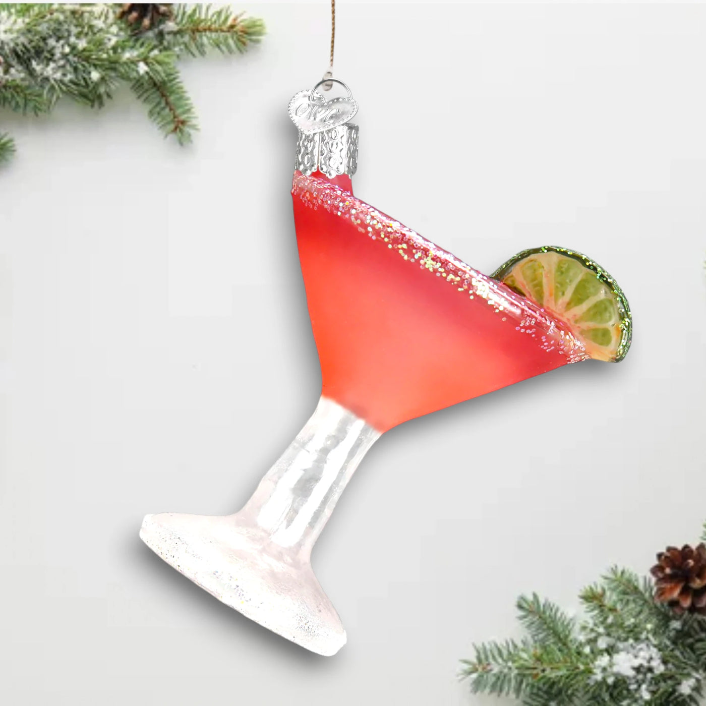 Cosmopolitan cocktail Christmas ornament featuring a vibrant pink drink, glittered sugared rim, and lime wedge garnish in a clear glass.