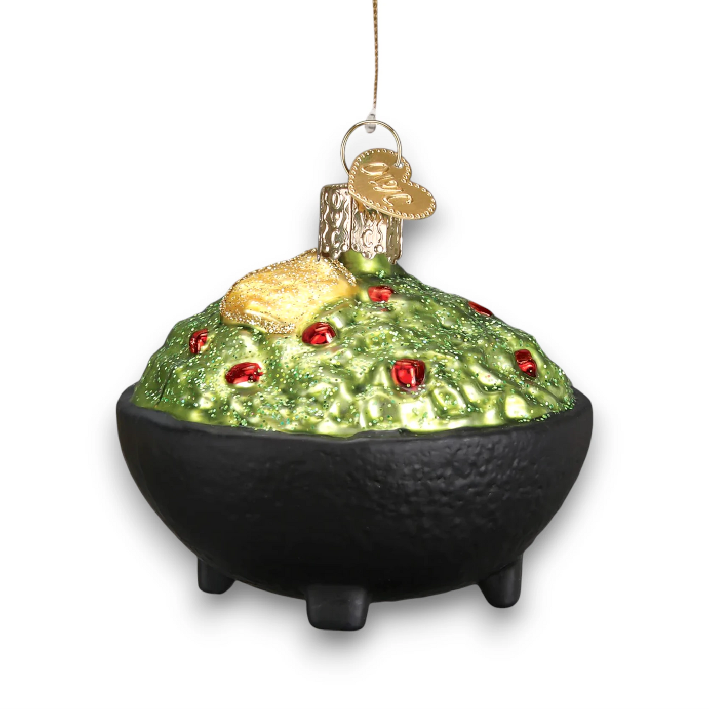 A glittery Christmas ornament depicting a bowl of guacamole with a golden tortilla chip on top, detailed with red accents and a black bowl base.