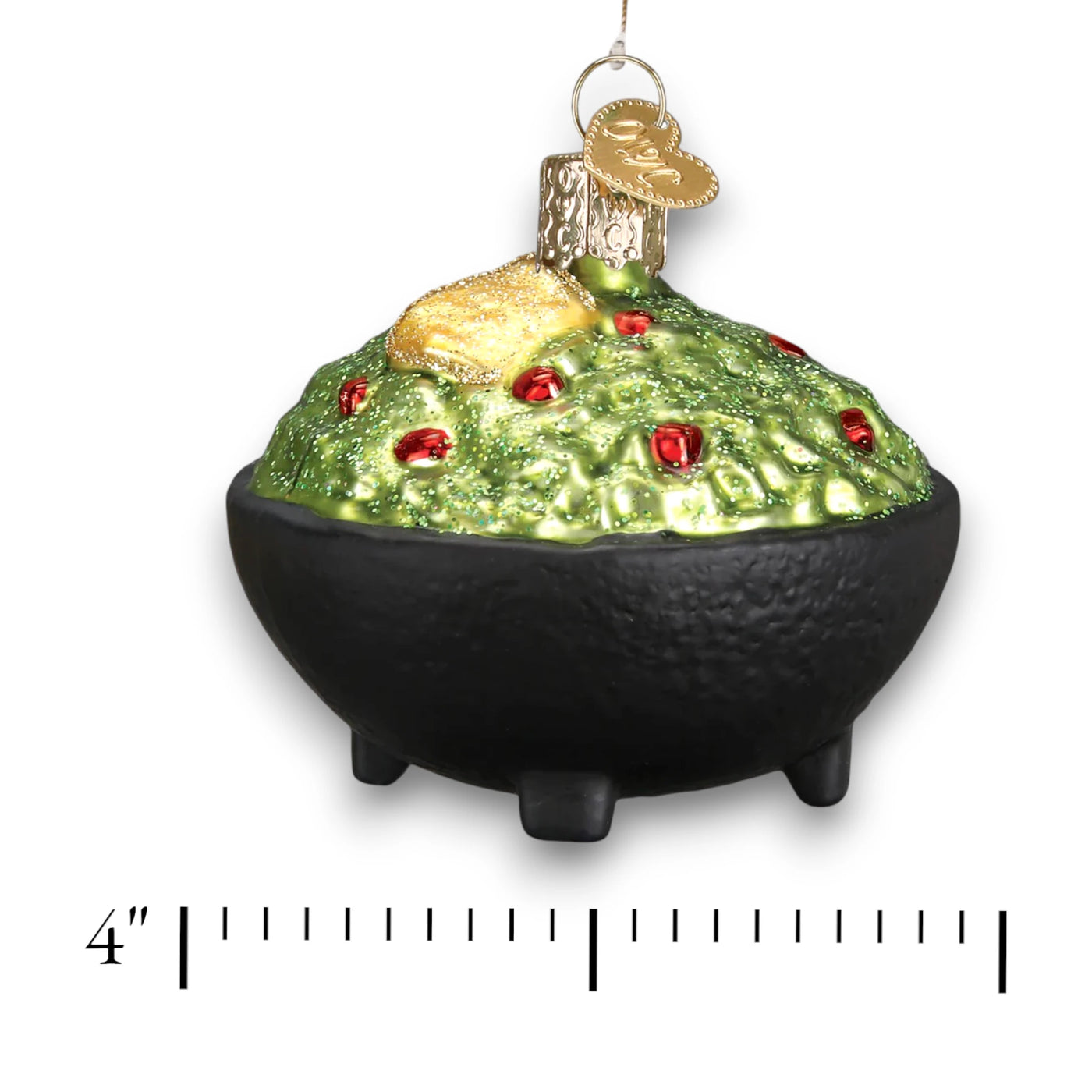 A glittery Christmas ornament depicting a bowl of guacamole with a golden tortilla chip on top, detailed with red accents and a black bowl base.