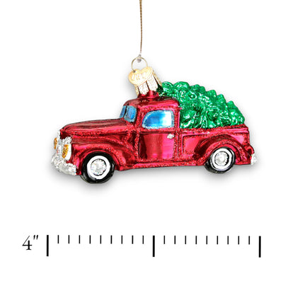 Vintage red truck Christmas ornament carrying a green tree with glitter accents, perfect for holiday decor and gifting.