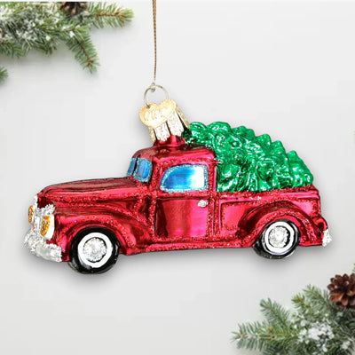 Vintage red truck Christmas ornament carrying a green tree with glitter accents, perfect for holiday decor and gifting.