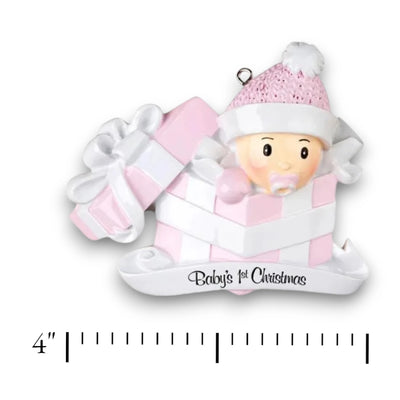 Personalized Baby Girl In Present Ornament with pink knit hat, peeking from a pink and white gift box, customizable with name and year.