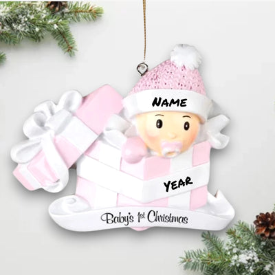 Personalized Baby Girl In Present Ornament with pink knit hat, peeking from a pink and white gift box, customizable with name and year.