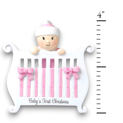 Personalized Baby Girl in Crib Christmas Ornament with customizable name and year, featuring a baby girl peeking over a crib with pink bows and glitter accents.