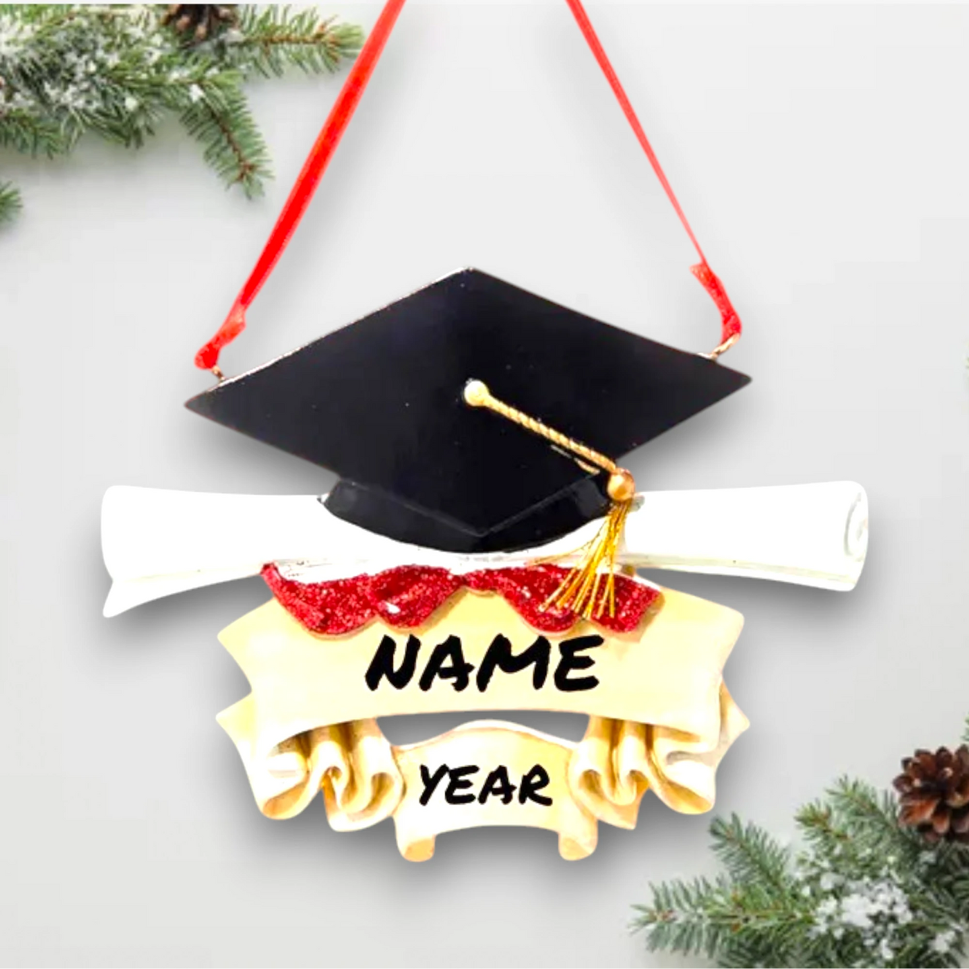 Personalized graduation ornament with a black mortarboard cap, gold tassel, diploma scroll, and customizable ribbon banner.
