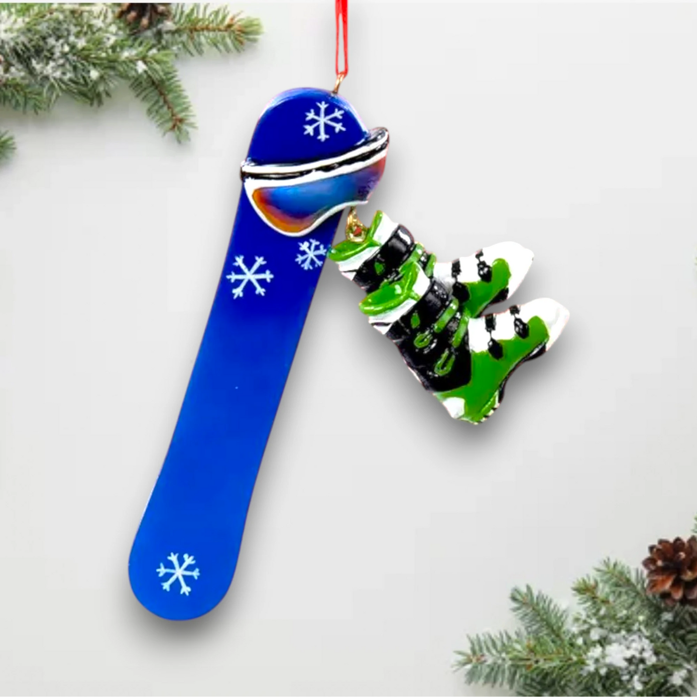 Personalized Snowboard Christmas Ornament featuring a blue snowboard with white snowflake details and dangling green snowboard boots, customizable with name and year.
