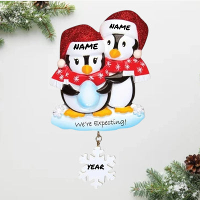  Personalized We're Expecting Penguins Christmas Ornament with customizable names and year, featuring two penguins dressed in festive holiday attire with a snowflake charm.