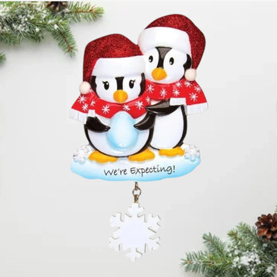  Personalized We're Expecting Penguins Christmas Ornament with customizable names and year, featuring two penguins dressed in festive holiday attire with a snowflake charm.