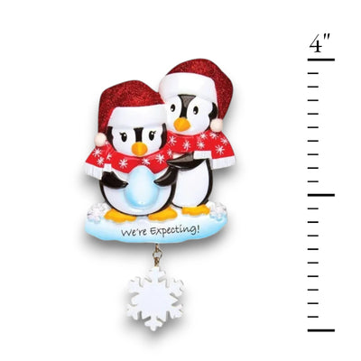  Personalized We're Expecting Penguins Christmas Ornament with customizable names and year, featuring two penguins dressed in festive holiday attire with a snowflake charm.