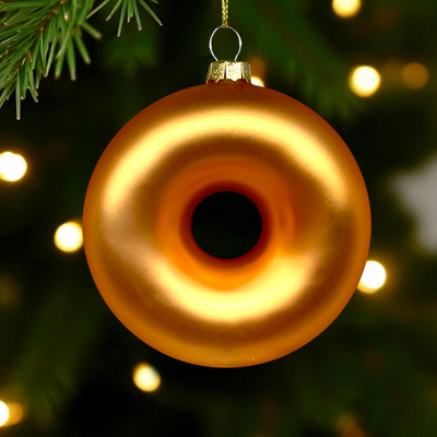 Decorative donut ornament hanging on a Christmas tree with blurred lights in the background.