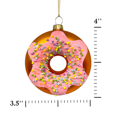 Decorative donut ornament with pink glaze and sprinkles, shown with a measurement ruler on a white background.
