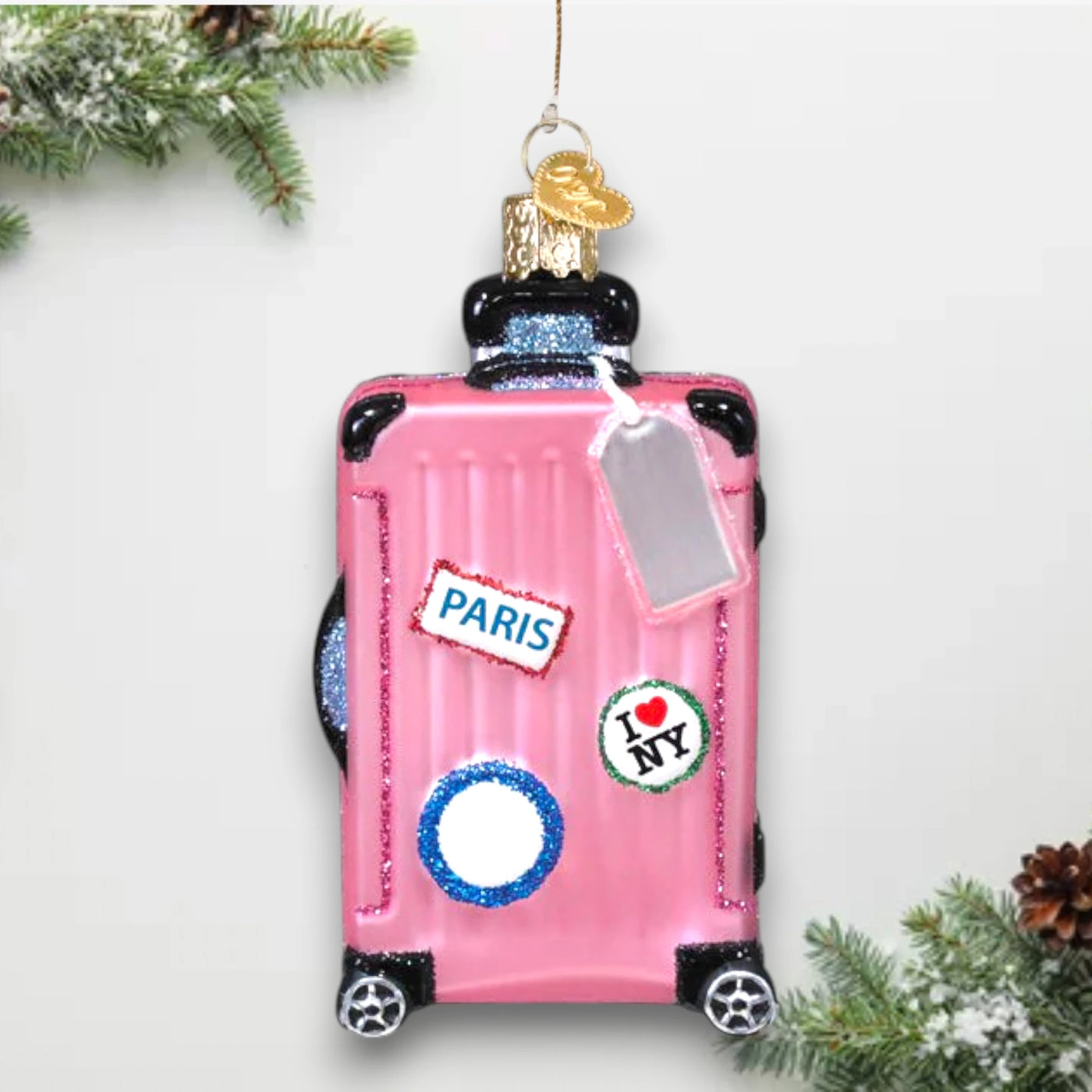 Personalized Pink Rolling Suitcase Christmas Ornament featuring a pink suitcase with travel stickers, glitter details, and a silver luggage tag, customizable with a name or year.