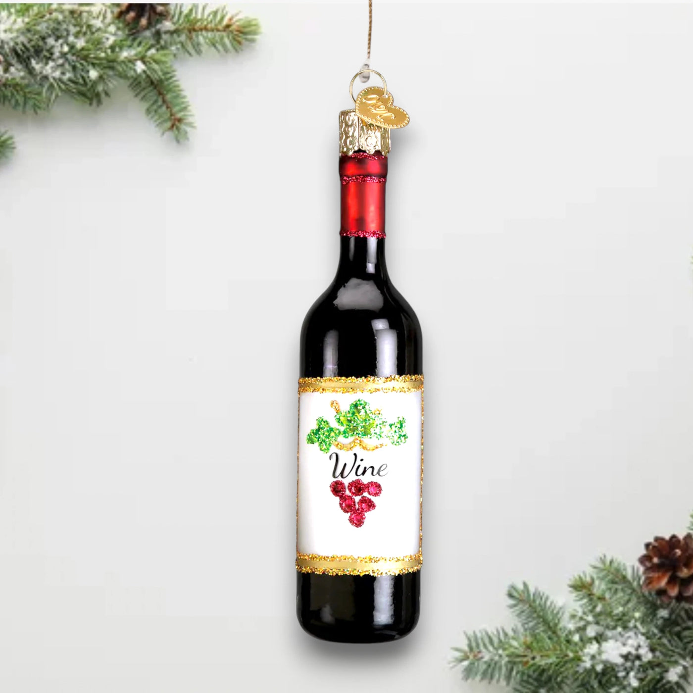 Red wine bottle Christmas ornament featuring a glossy finish, glitter-accented label with grape details, and a festive gold trim.