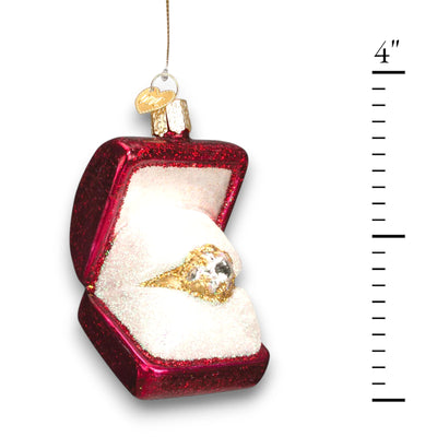 Christmas ornament featuring a glittering gold ring in a red jewelry box with shimmering details, symbolizing love and celebration.