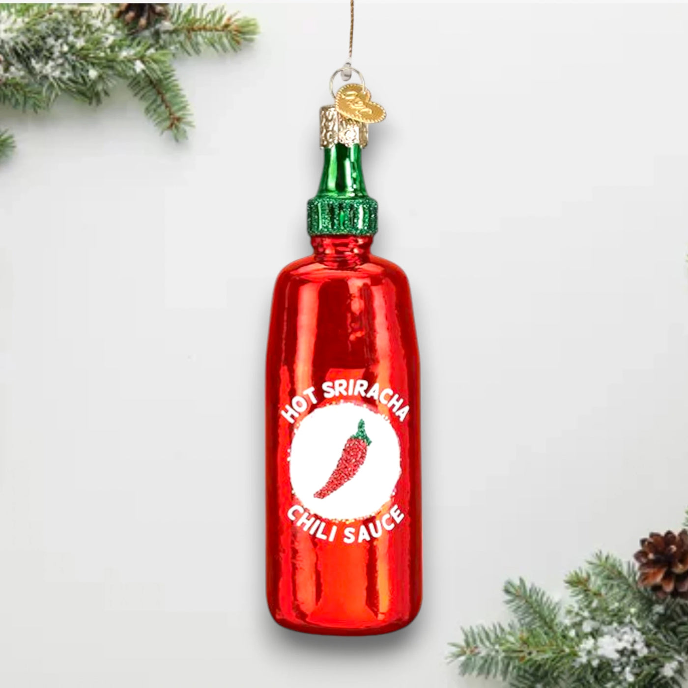 Sriracha Sauce Christmas ornament featuring a bright red bottle with a green cap, glitter accents, and iconic chili pepper label.