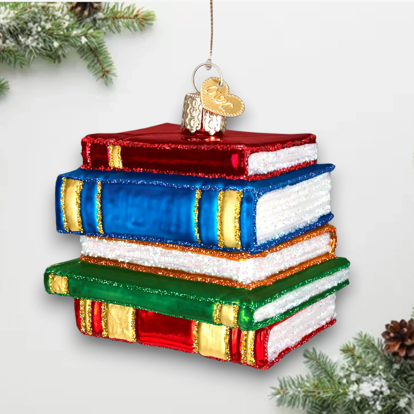 Christmas ornament featuring a stack of books in red, blue, and green with sparkling glitter accents, ideal for book lovers and teachers.